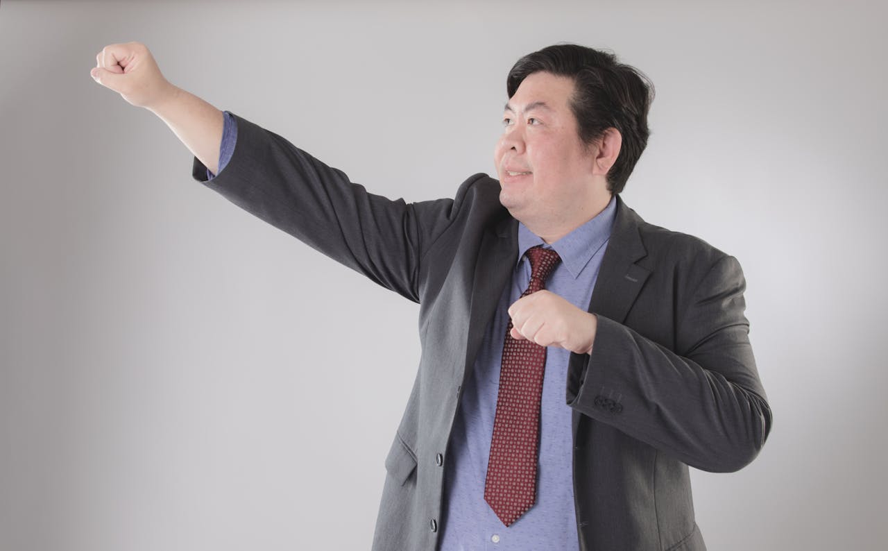 A confident businessman in a suit strikes a powerful and dynamic pose against a gray background.